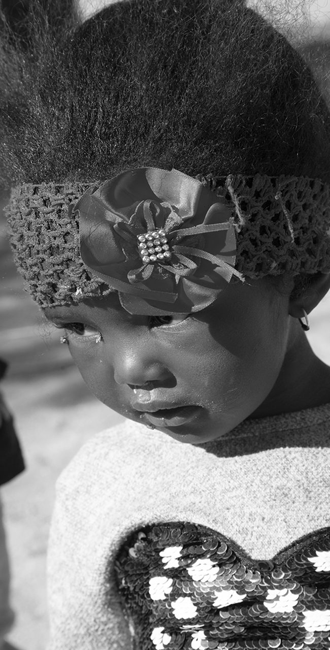 des yeux semblent observer le monde avec une profonde innocence. La photo, en noir et blanc, saisit l'instant avec une grande tendresse.