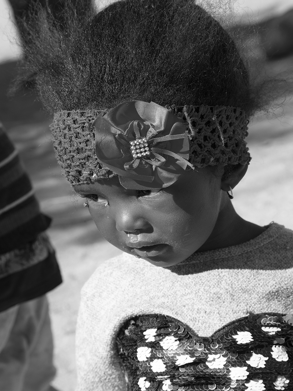 des yeux semblent observer le monde avec une profonde innocence. La photo, en noir et blanc, saisit l'instant avec une grande tendresse.